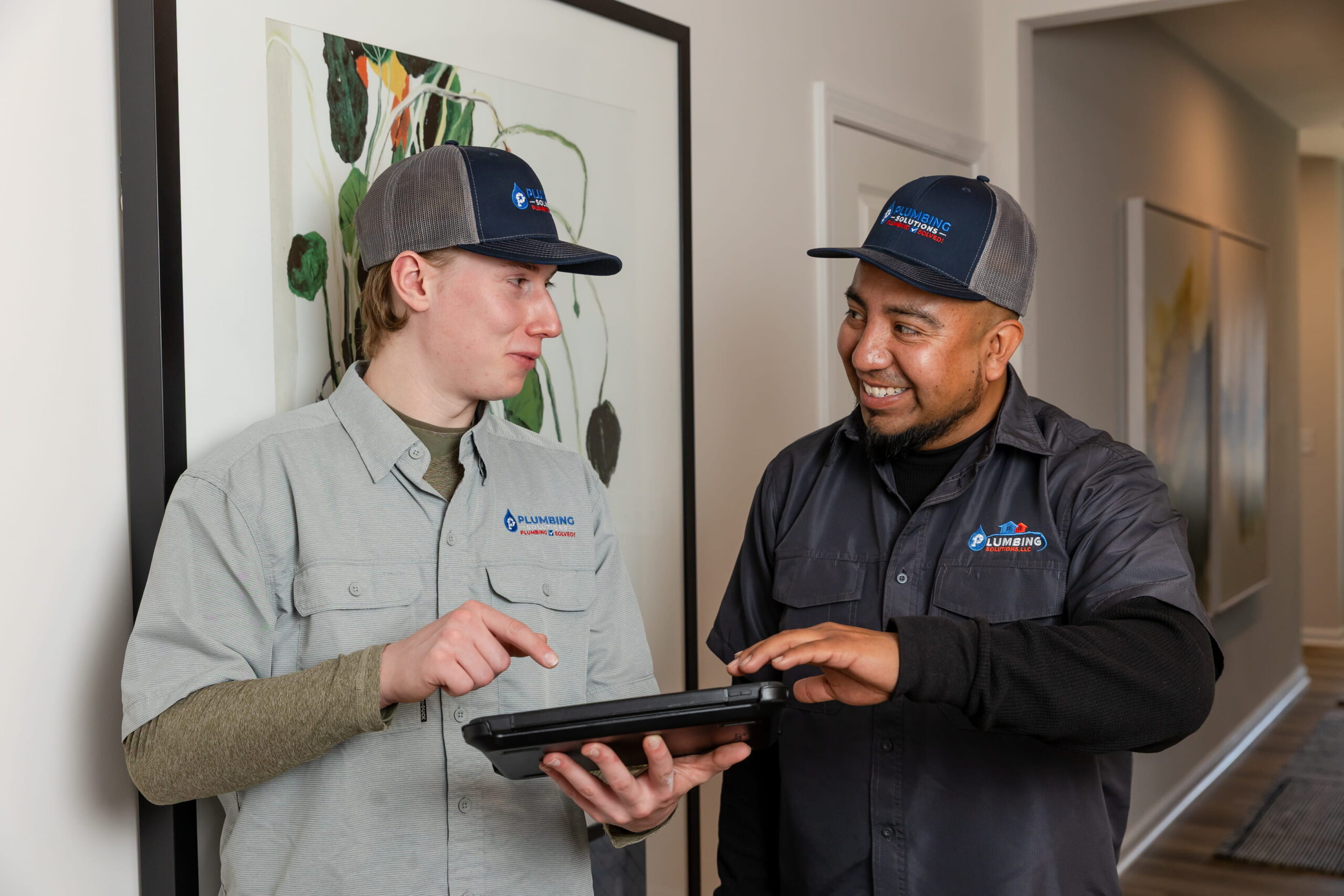 Plumbing Solutions LLC plumbers reviewing job details on a tablet