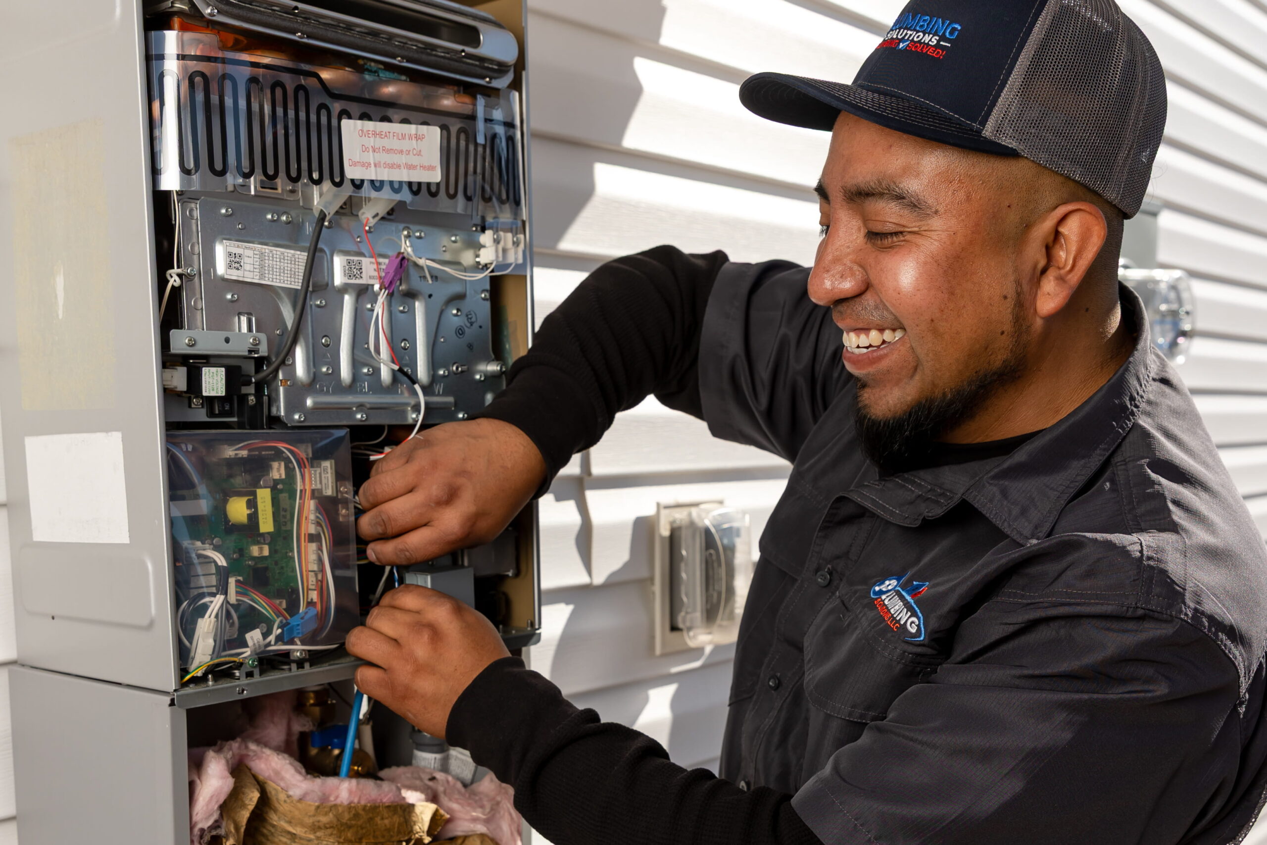 Plumbing Solutions LLC plumber servicing an outdoor tankless water heater