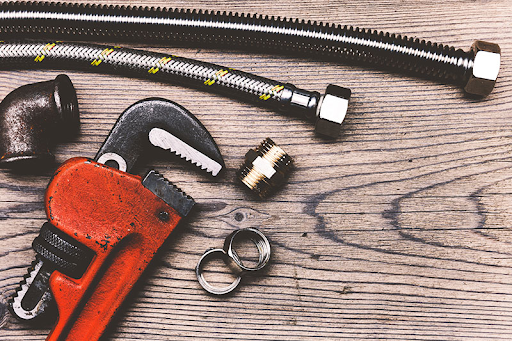 Plumbing Solutions LLC plumbing tools including wrench pipe fittings and hose prepared for water heater repair service.