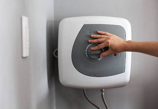 Homeowner adjusting temperature settings on a wall mounted tankless water heater installed by Plumbing Solutions LLC.