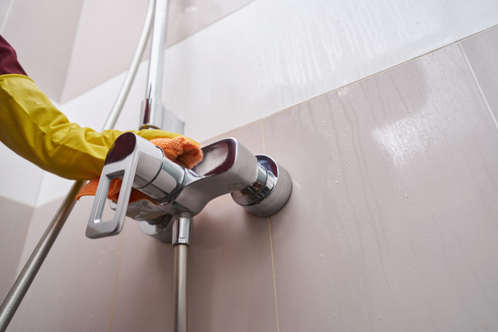 Plumbing Solutions LLC technician cleaning and servicing a shower valve fixture after professional replacement work.