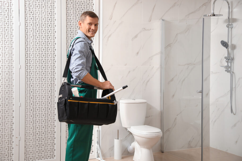 Plumbing Solutions LLC plumber preparing tools for bathroom plumbing repair near shower and toilet fixtures.