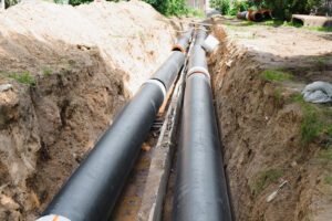 Plumbing Solutions LLC crew installing a new underground sewer line in an open trench during residential sewer replacement.
