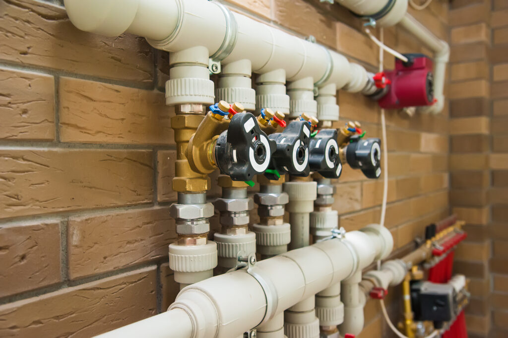 Multi-zone water manifold with shutoff valves and pressure controls installed on exterior wall.