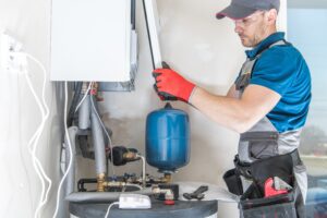 Technician servicing a residential water heater and expansion tank during a plumbing inspection for Plumbing Solutions LLC.