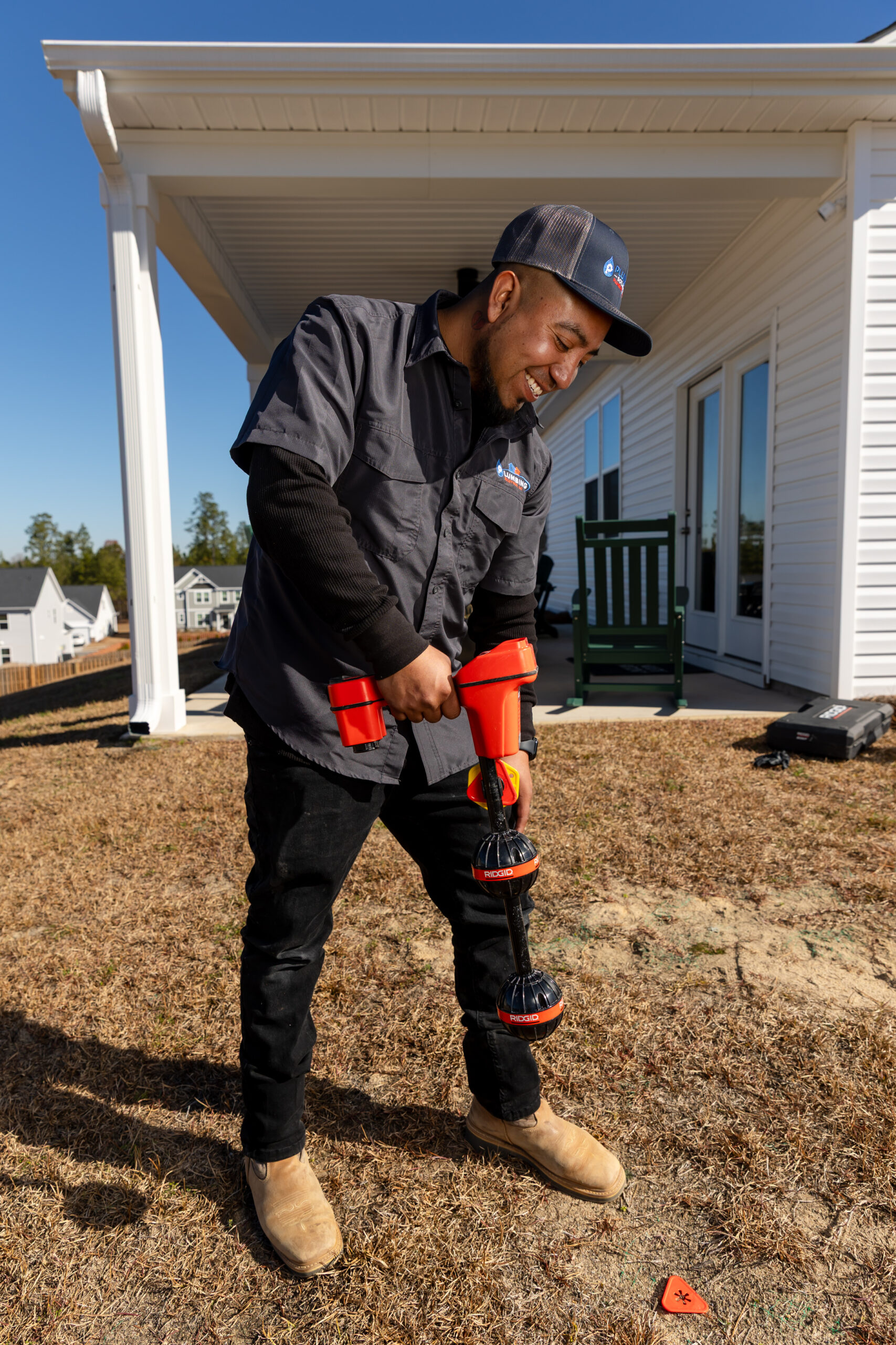 Plumbing Solutions LLC plumber using pipe-cutting tools during a residential repiping project outdoors.
