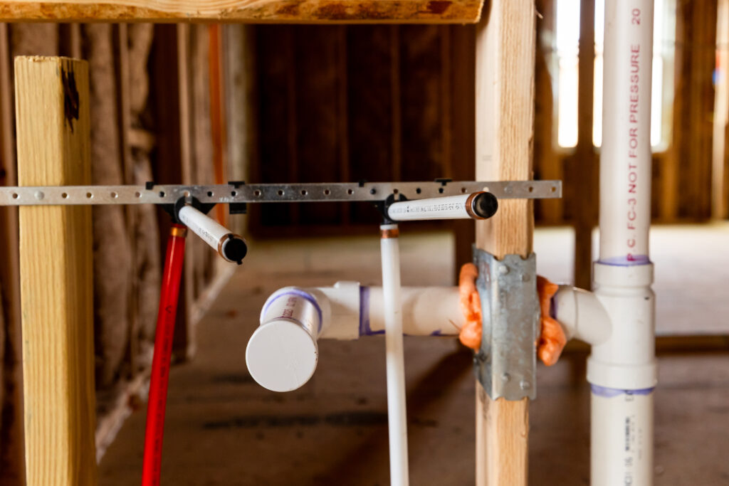 Rough-in plumbing installation showing drain lines and water supply piping in a residential construction project.