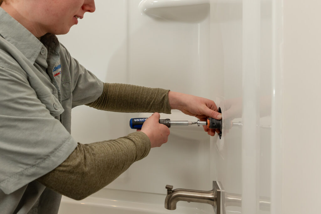 Plumbing Solutions LLC technician works on a shower faucet valve during a bathroom plumbing repair.