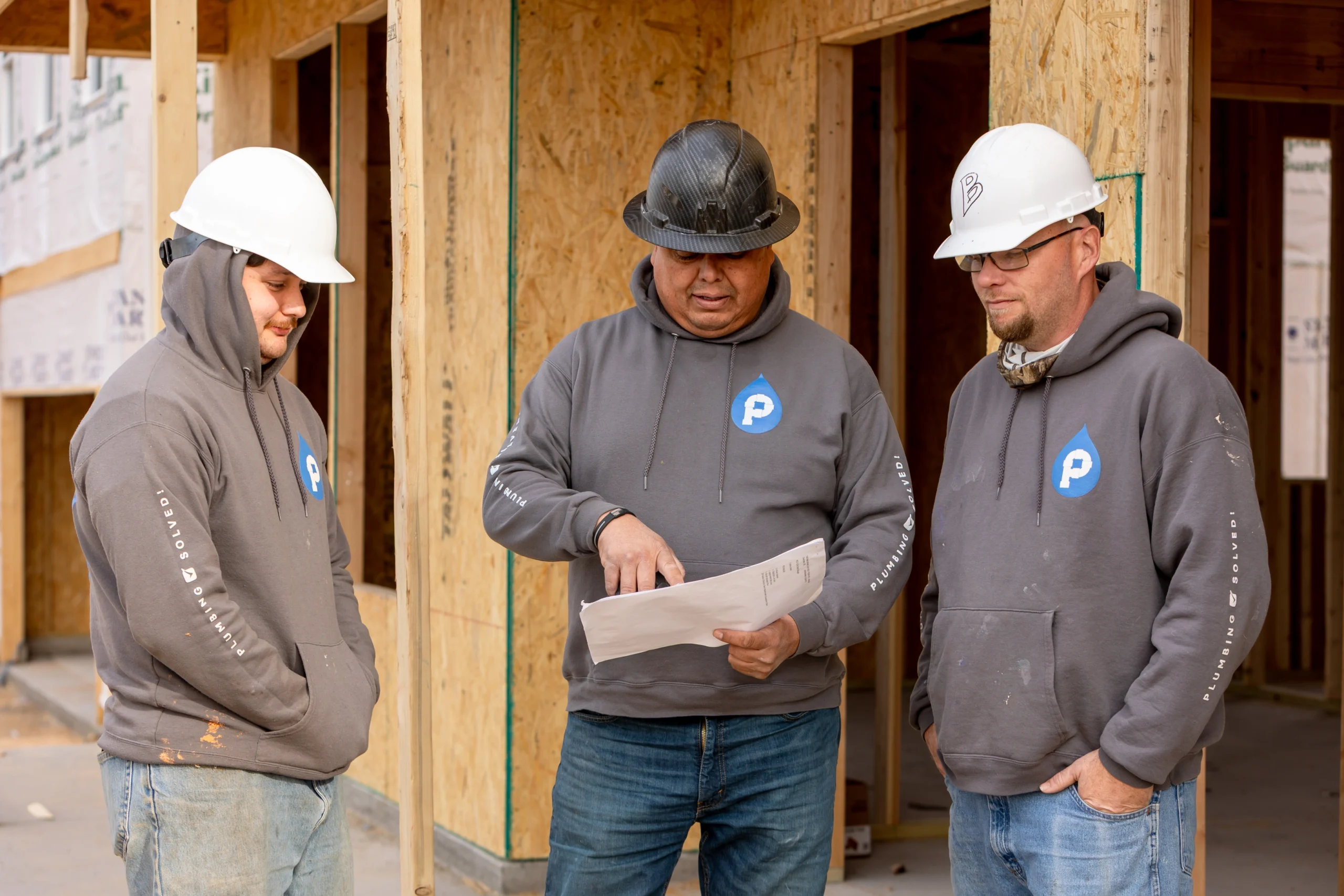 Plumbing professionals inspecting a residential plumbing system to identify potential repairs before a holiday weekend.