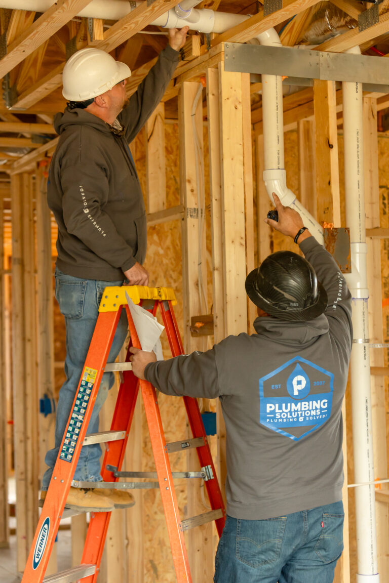 Plumbing Solutions LLC technicians installing new water supply lines during a whole-house repiping project in a home's exposed framing.