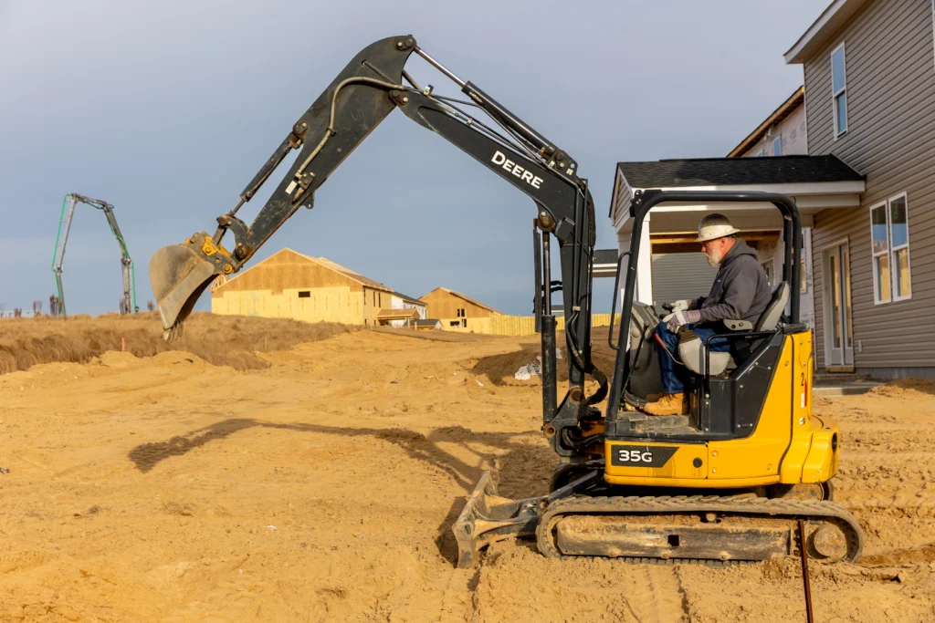 Worker excavating beneath a concrete slab to access and repair an underground plumbing leak.