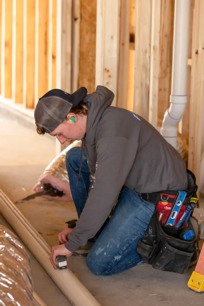 Plumbing professional repairing a leaking pipe and inspecting the area for slab leak damage.