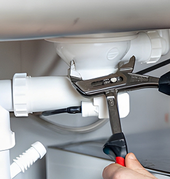 Plumber repairing pipes under a sink